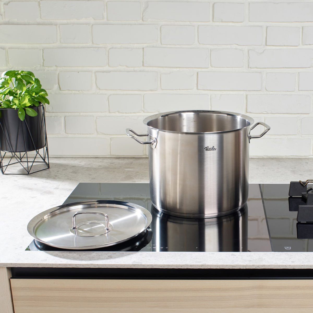 Original-Profi Collection® tall Cooking Pot with Cookstar All-Stove Base by Fissler on a modern stove, basil in the background.
