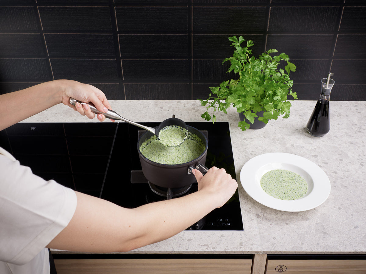 The green soup is served in a bowl from an Adamant® Cookware Set by Fissler - German precision cookware since 1845 - with parsley and sauce beside it.