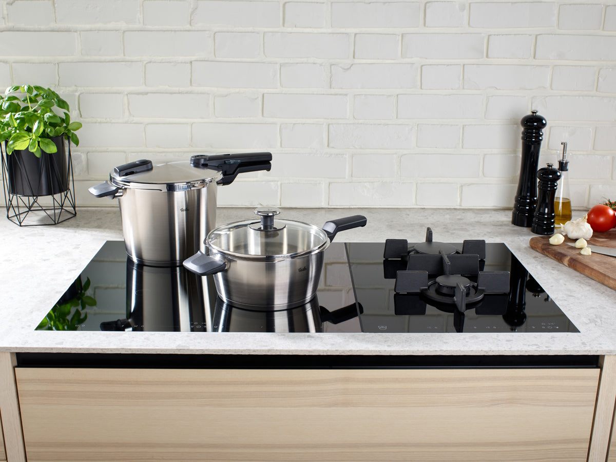 Fissler Vitaquick® Premium 2-teiliges Schnellkochtopf-Set auf schwarzem Glaskochfeld; hochwertiges deutsches Kochgeschirr in einem stilvollen Küchenambiente.