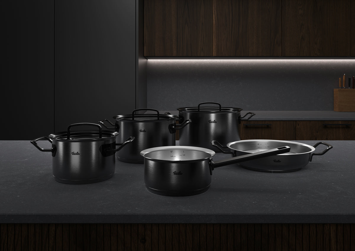 Das 5-teilige Fissler Original-Profi Collection® Shadowline Set aus rostfreiem Edelstahl, hergestellt in Deutschland, auf einer eleganten Theke mit Holzakzenten.