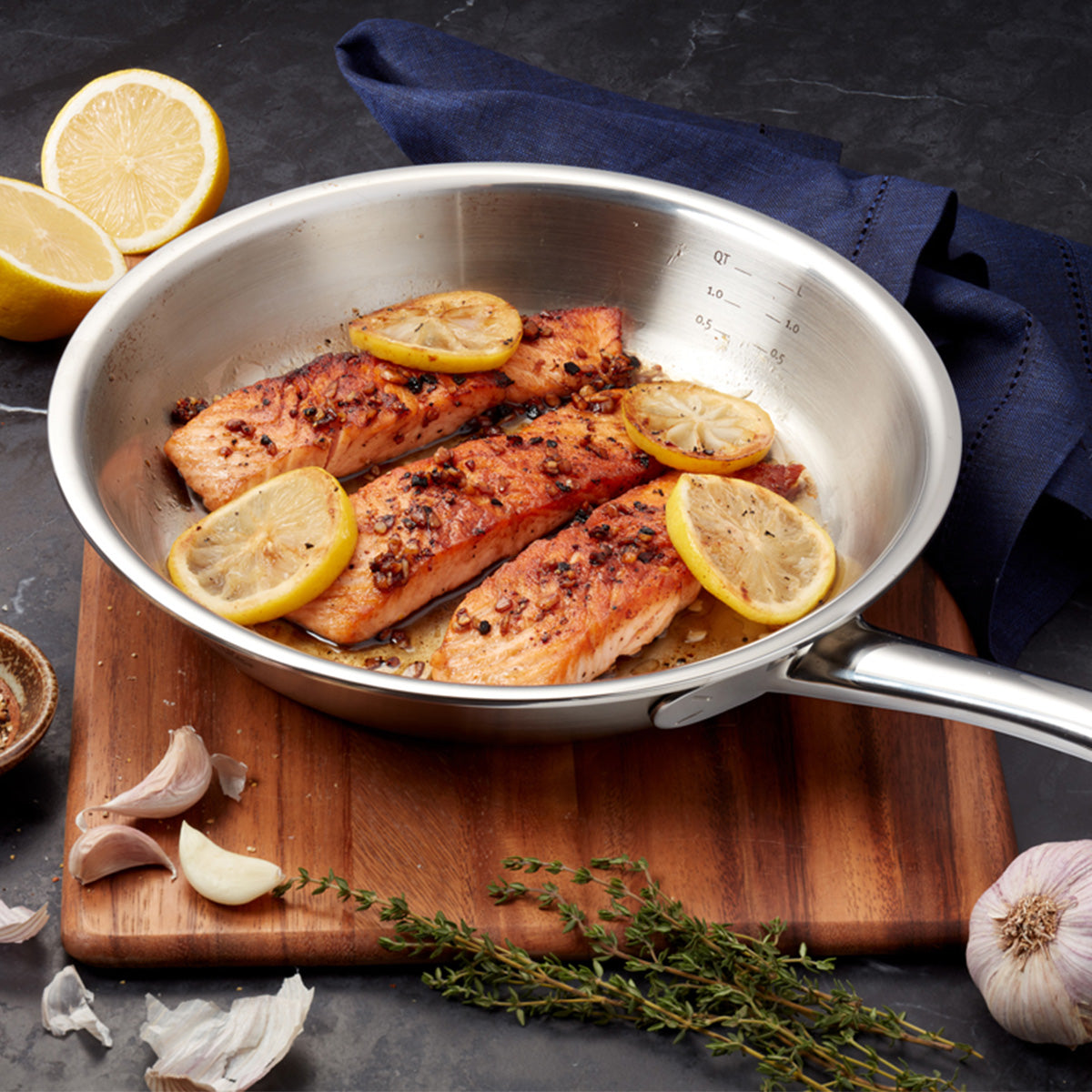 Expertly prepared salmon fillets with lemon slices and aromatic spices are beautifully presented in the Fissler M5 Pro-Ply® 3-piece set with stainless steel lid, highlighting German engineering and timeless design.