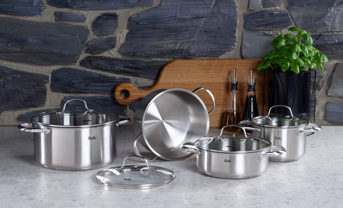 Ein Set aus Fissler San Francisco-Kochgeschirr aus Edelstahl mit Deckeln, das die Tradition der Marke in Sachen Präzisionstechnik und zeitlosem Design verkörpert, angeordnet auf einer Arbeitsplatte.