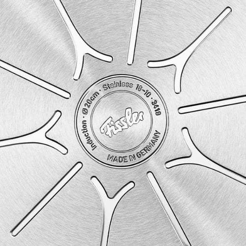 Detail of the Fissler stainless steel pan base, precision-etched lines, "Made in Germany" trademark, suitable for induction.